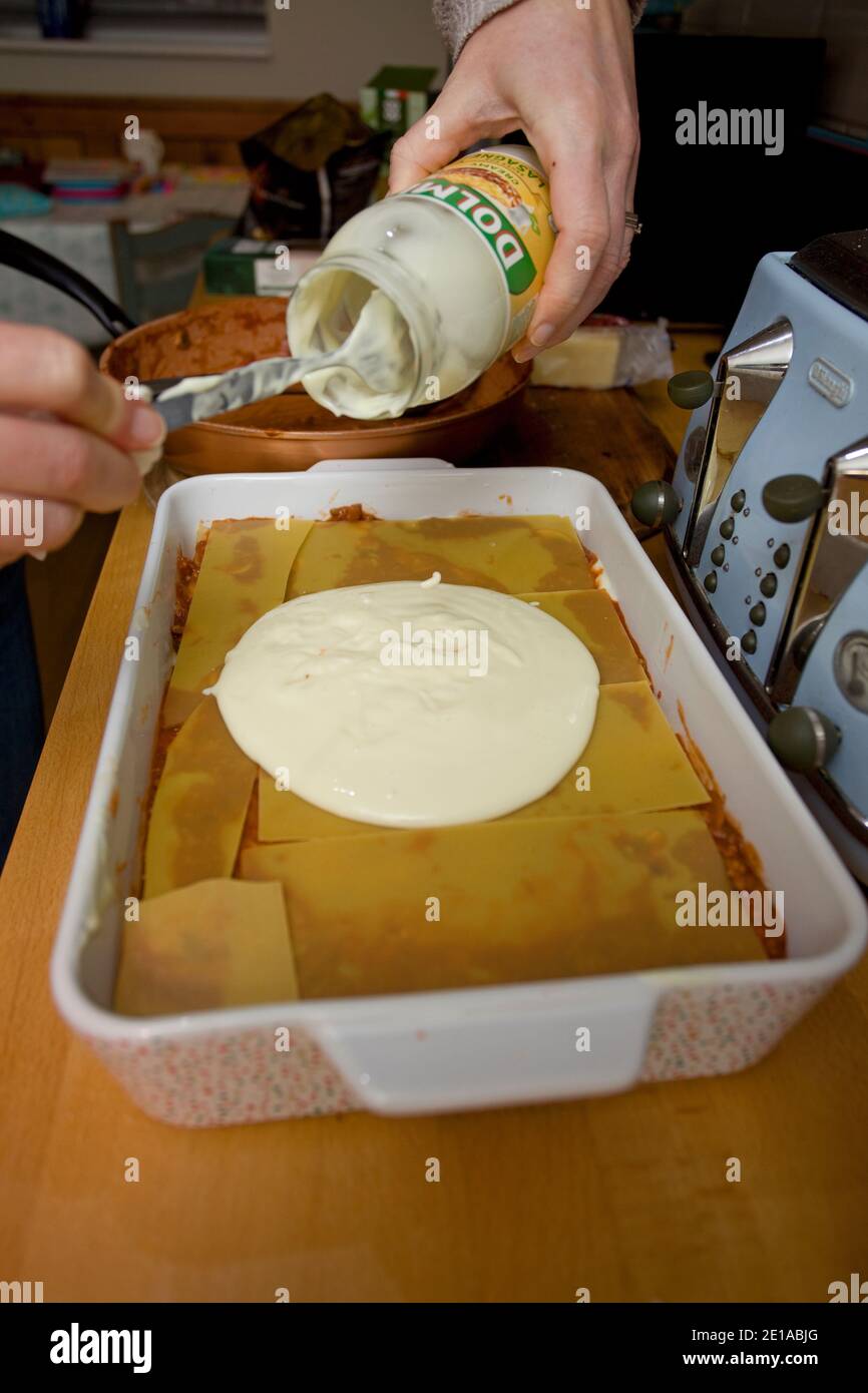 Versare la salsa di lasagne Dolmio sulla pasta cruda. Inghilterra Foto Stock