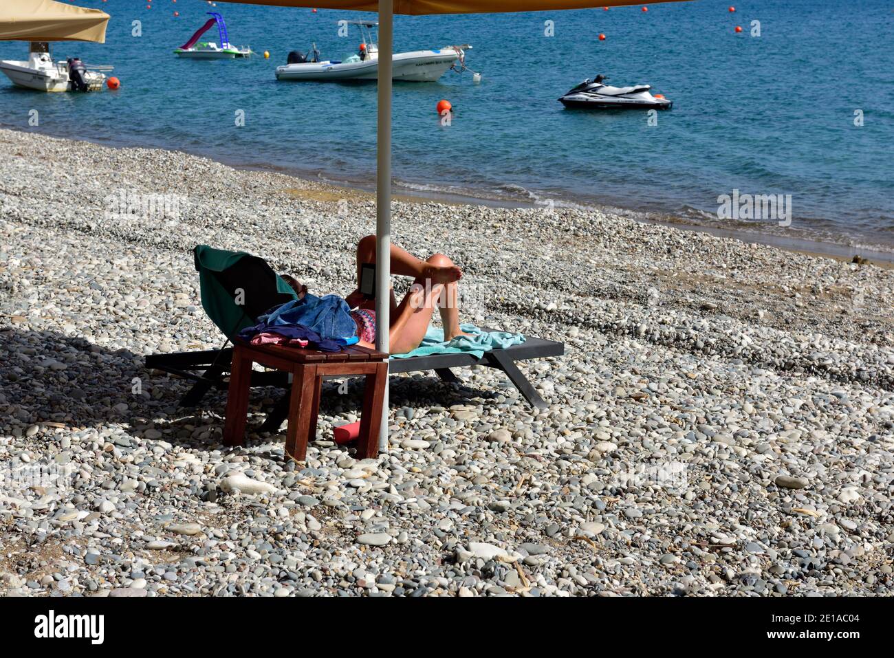 Spiaggia di ciottoli con sdraio sotto ombrellone, Cipro, Europa Foto Stock