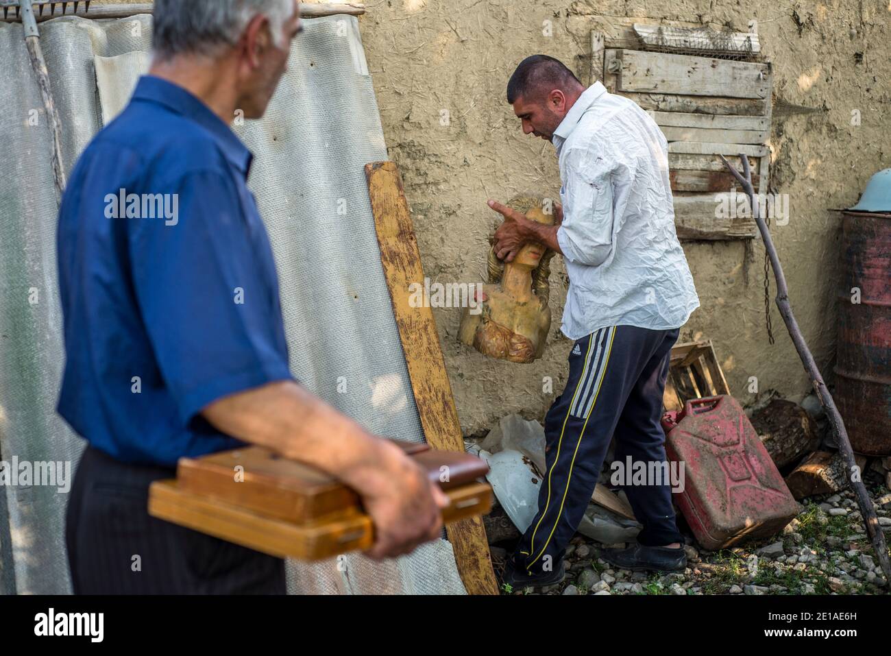 Un woodcarver Rufet Hanahmeydov sta lavorando alla sua nuova creazione nel villaggio di Anig, distretto di Qusar, Azerbaigian. È stato intagliatura e pittura del legno per quasi 45 anni. Rufet dice che prende tutte le idee dai suoi sogni. Ora Rufet sta intagliando un ragazzo che tiene la mano e grida perché è stato morso da una vespa. Foto Stock