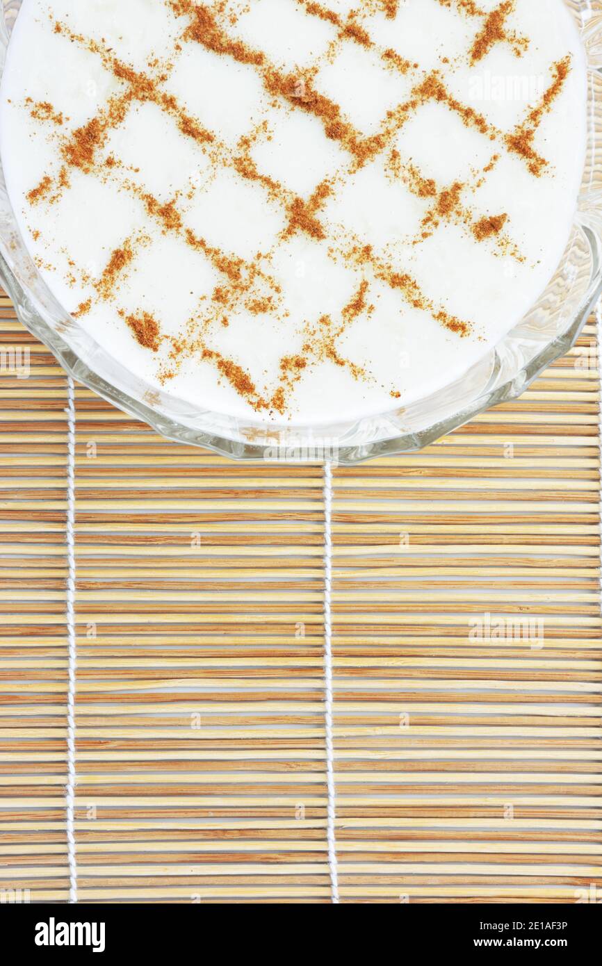 Budino di riso cremoso alla cannella su tappetino di paglia di bambù come sfondo Foto Stock