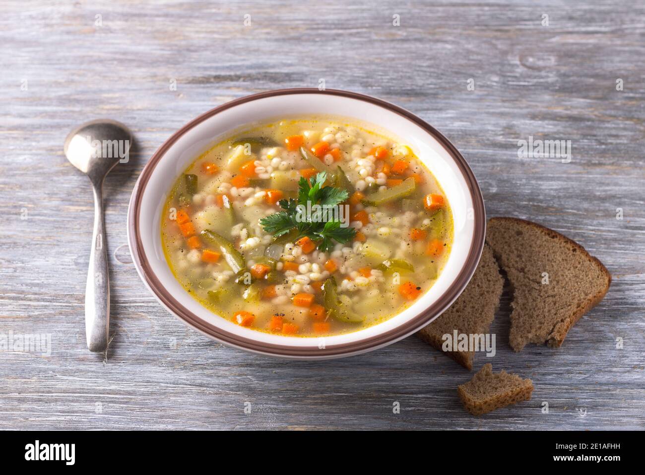 Zuppa vegana con cetrioli sottaceto e orzo perlato, rassolnik. Cucina tradizionale russa fatta in casa. Su un tavolo di legno Foto Stock