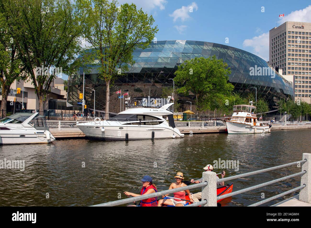 Ottawa, Canada - 4 agosto 2012: La gente pagaia sul canale di Rideau con lo Shaw Center, un centro congressi sullo sfondo. Foto Stock