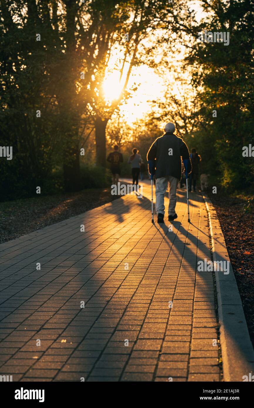 Un percorso acciottolato in controluce alla fine della giornata è attraversato da passanti. Foto Stock