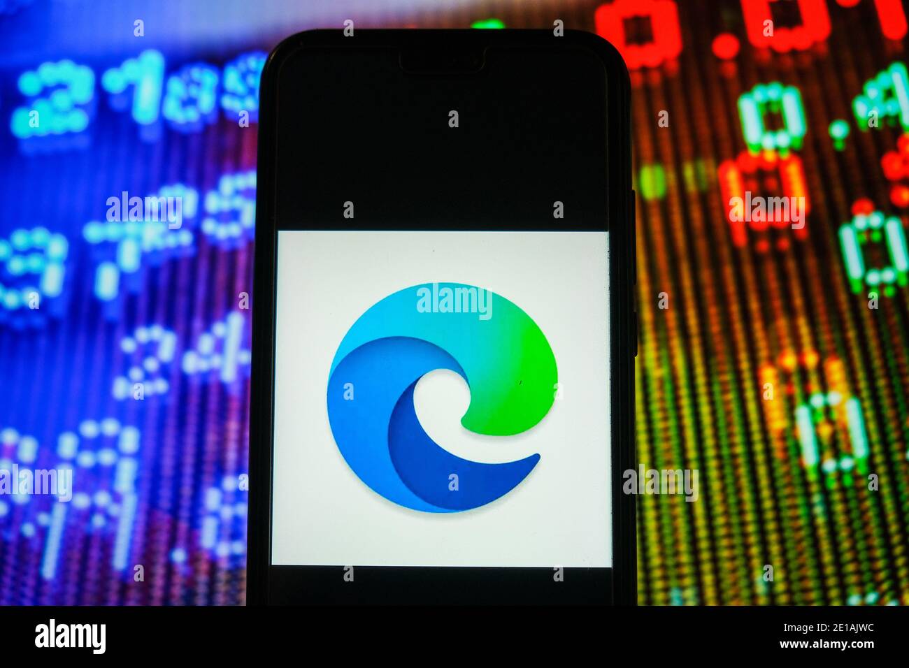 In questa illustrazione fotografica, viene visualizzato un logo Microsoft Edge su uno smartphone con i prezzi azionari in background. Foto Stock