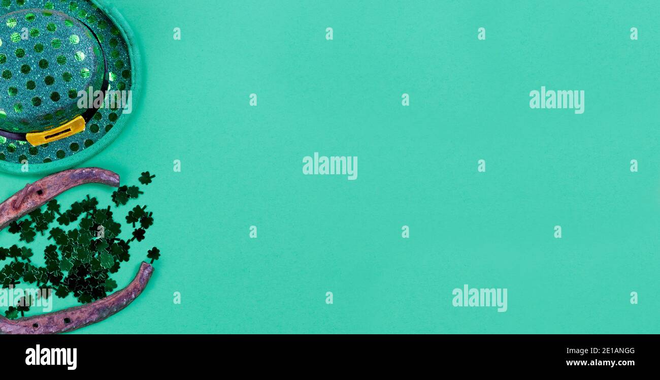 Festa di festa di San Patrizio con elfo irlandese, scarpe da cavallo e piccoli trifogli su sfondo di carta verde con spazio per la copia Foto Stock