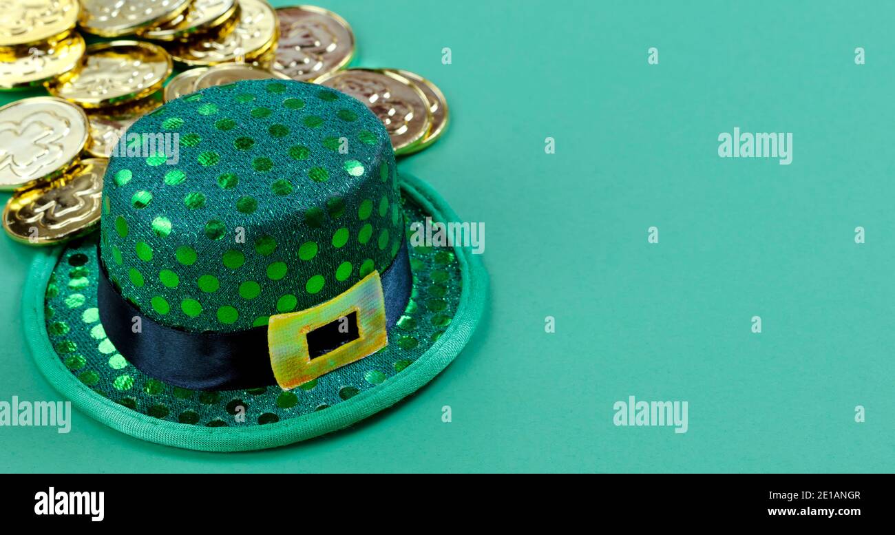 Primo piano di un elfo irlandese del giorno di St Patricks e monete d'oro lucido sullo sfondo verde con spazio di copia Foto Stock