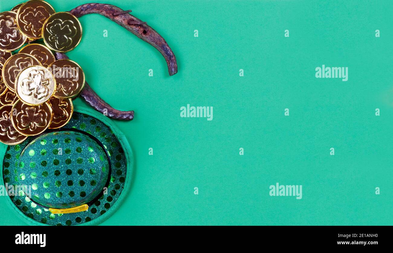 Cappello irlandese, scarpa da cavallo e monete d'oro del giorno di San Patrizio su sfondo di carta verde con spazio per la copia Foto Stock