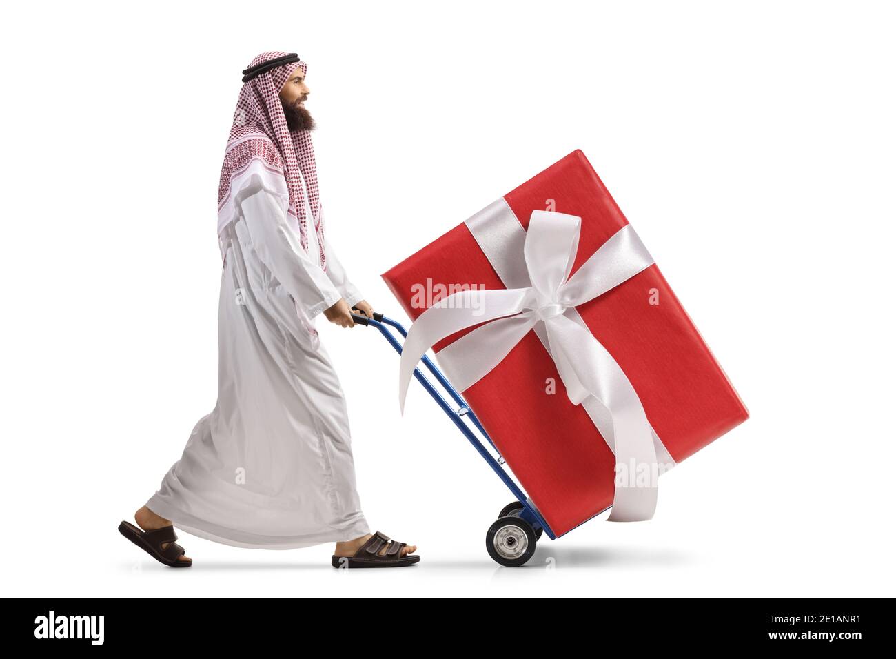 Uomo arabo Saudita che spinge un camion a mano con un grande scatola presente avvolta isolata su sfondo bianco Foto Stock