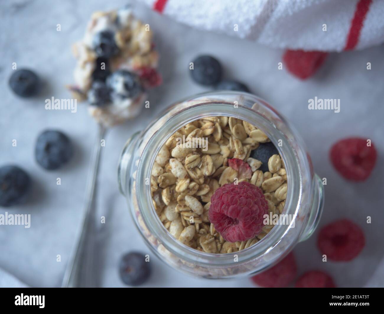 Piatto di parfait yogurt con lamponi di mirtilli alla granola in un vaso, cucchiaio accanto al vaso Foto Stock