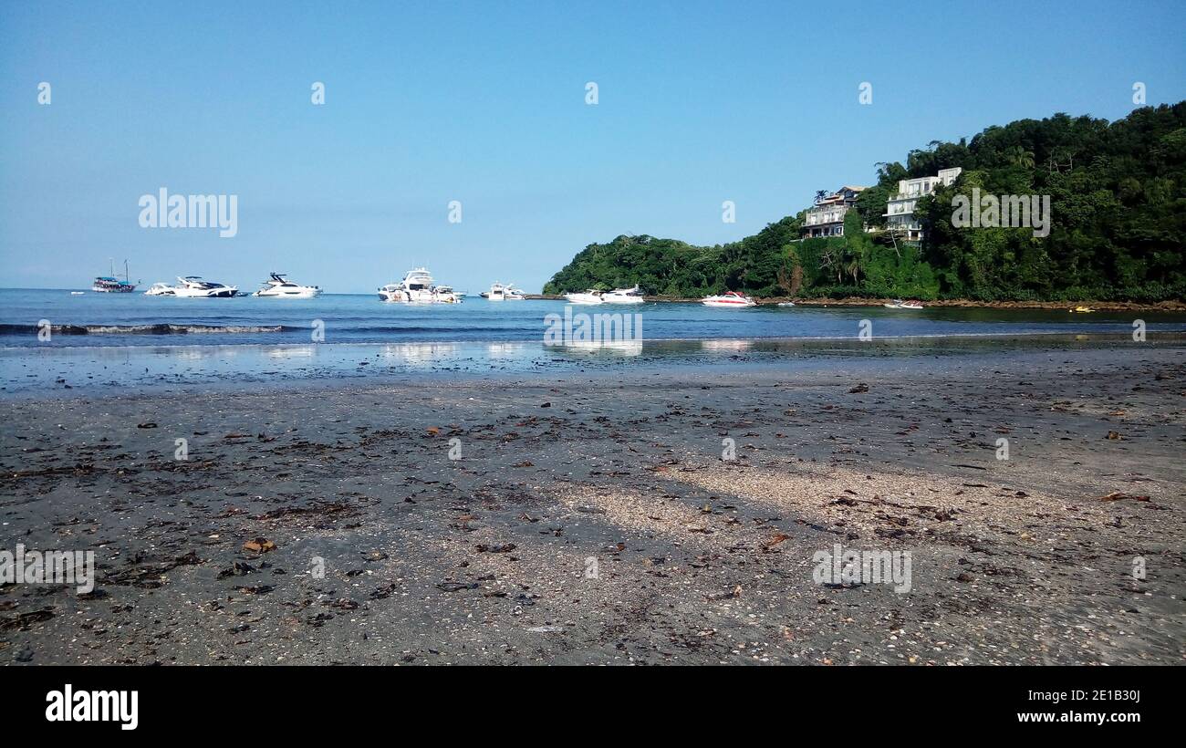 Barche bianche e due ville vicino spiaggia tropicale con vibrante cielo blu Foto Stock