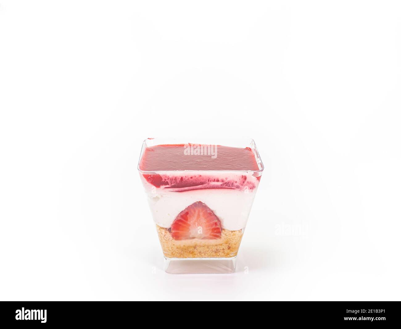 Il primo piano della cheesecake alla fragola in una tazza di plastica trasparente a forma quadrata isolata su sfondo bianco. Foto Stock