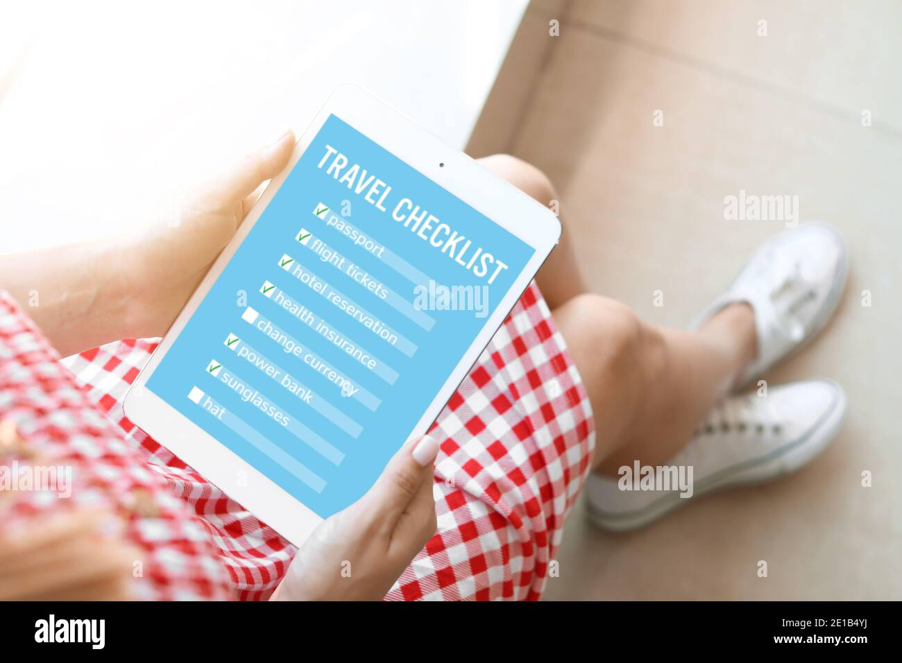 Donna con computer tablet che fa un elenco di controllo delle cose a. fare prima di viaggiare a casa Foto Stock