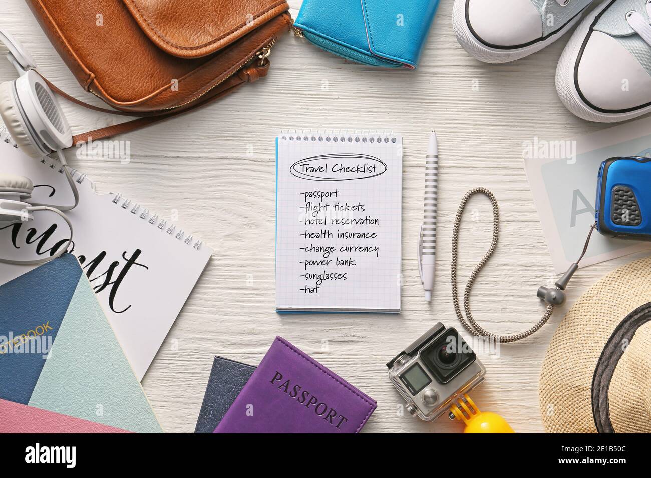 Notebook con elenco di controllo delle operazioni da eseguire prima di viaggiare su sfondo bianco di legno Foto Stock