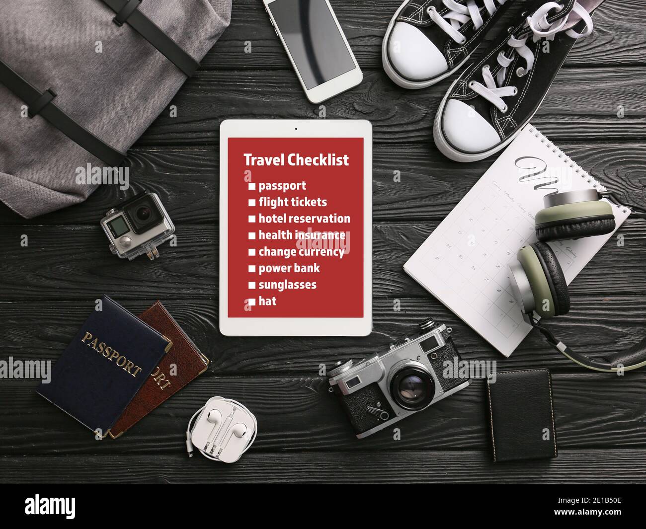 Tablet computer che fa un elenco di controllo delle cose da fare prima viaggiare sullo schermo su sfondo di legno scuro Foto Stock