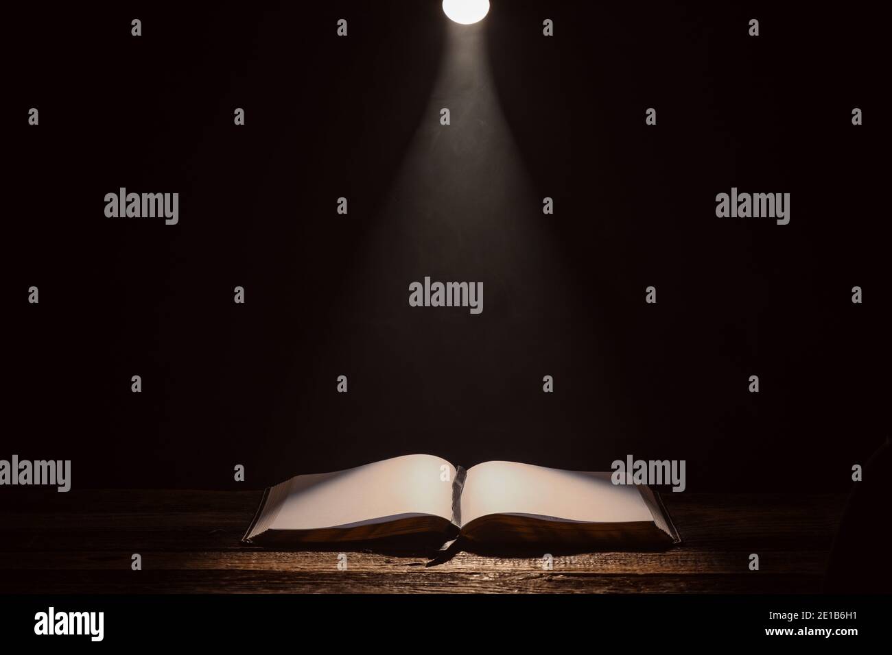 Libro aperto sulla tavola contro uno sfondo scuro Foto Stock