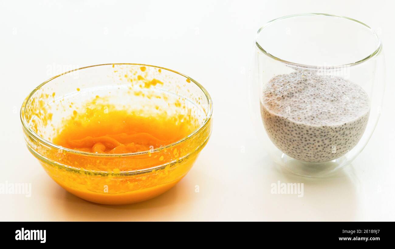 Purea di Mango e semi di Chia pudding primo piano in un ciotole di vetro su tavolo da cucina bianco Foto Stock