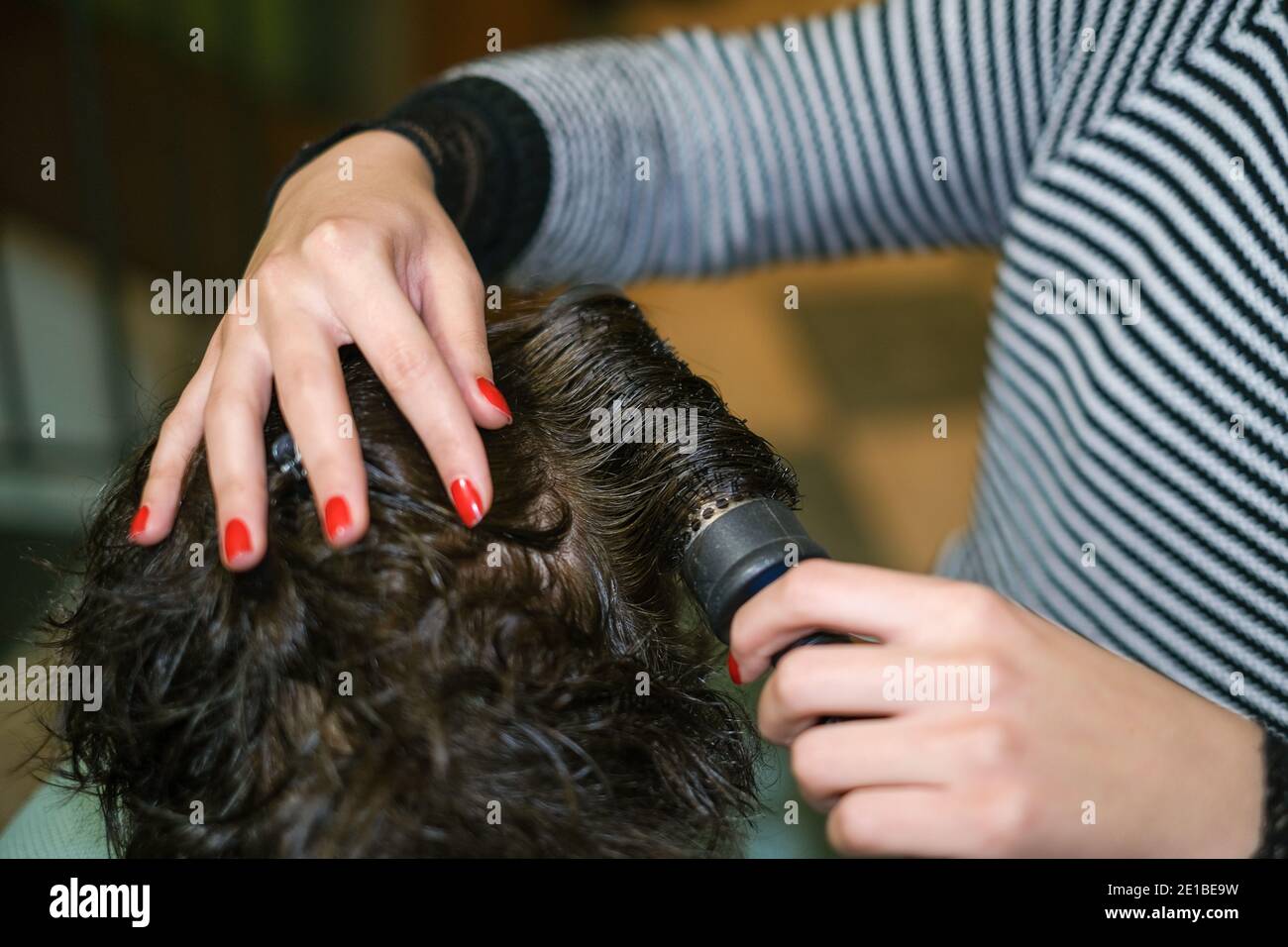 Hair dresser Donna mentre capelli che asciugano il cliente al lavoro, la bellezza domestica trattamento Foto Stock