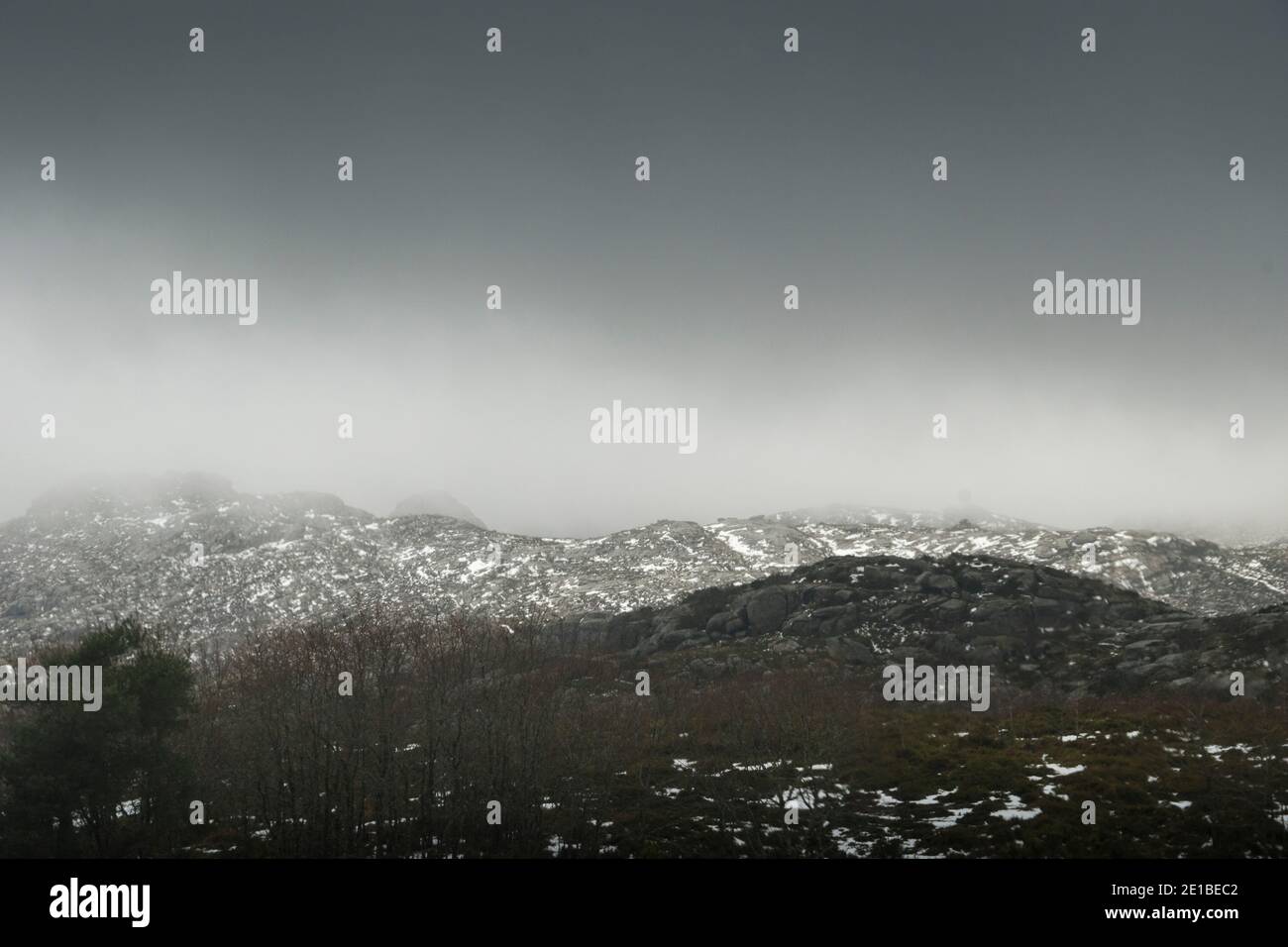 Paesaggio montano con capes nevosi in una giornata piovosa, come la luce entra attraverso le nuvole Foto Stock