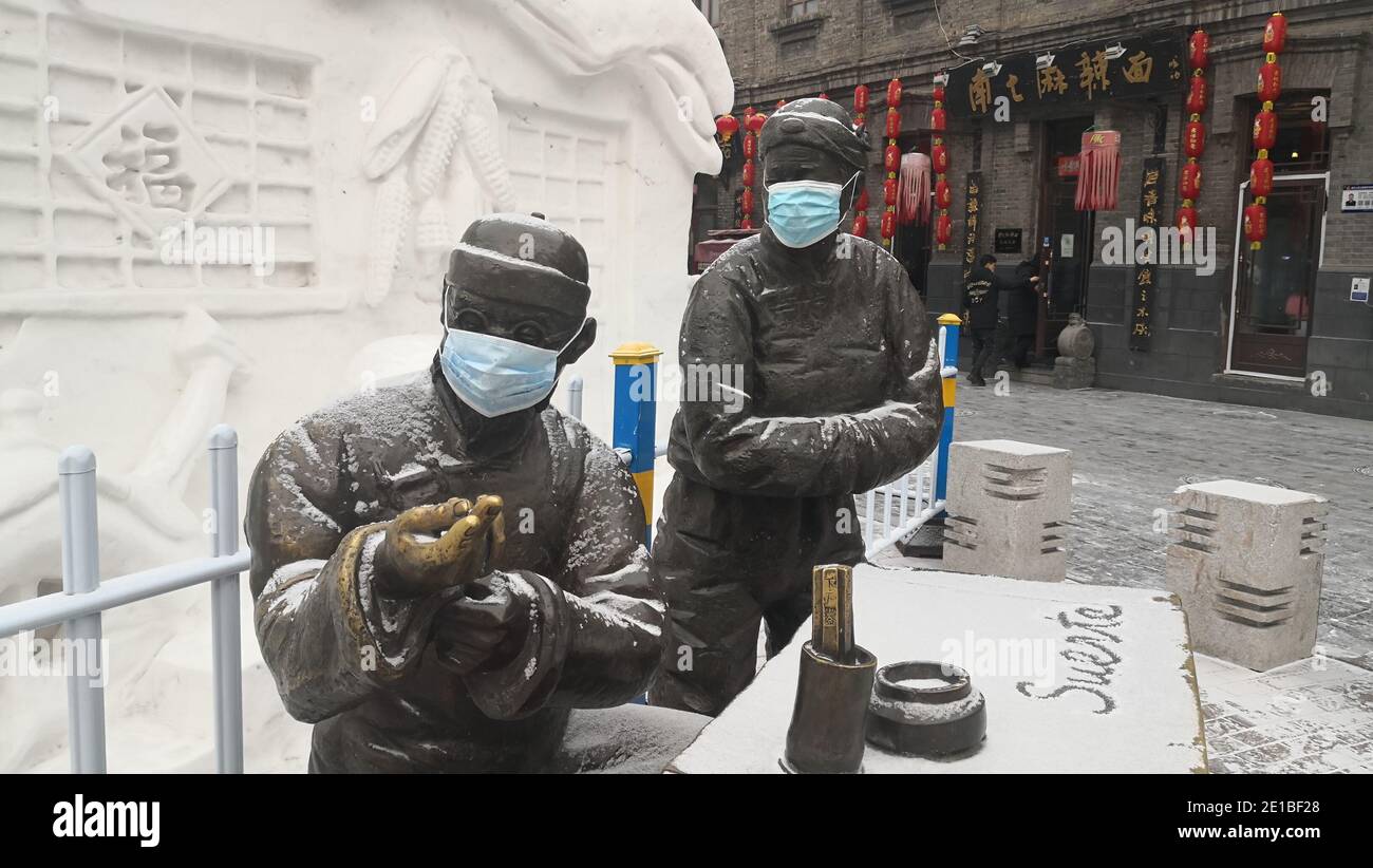 Bronzi statue situate in attrazione turistica locale sono visti indossare maschere, città Harbin, la provincia di Heilongjiang¯della Cina nord-occidentale, 6 gennaio 2021. *** Foto Stock