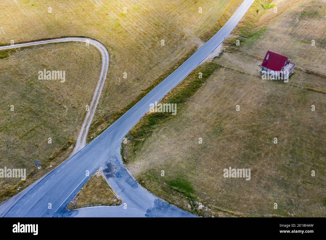 Bivio stradale e una casa di montagna isolata nei sentieri dei Sibillini in Italia. Vista aerea dall'alto della strada vuota. Valico S. Maria Maddalena Foto Stock