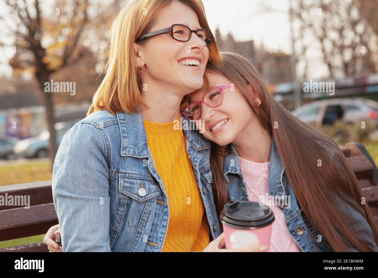 Madre e figlia felici ridendo e abbracciando all'aperto su un caldo giorno d'autunno Foto Stock