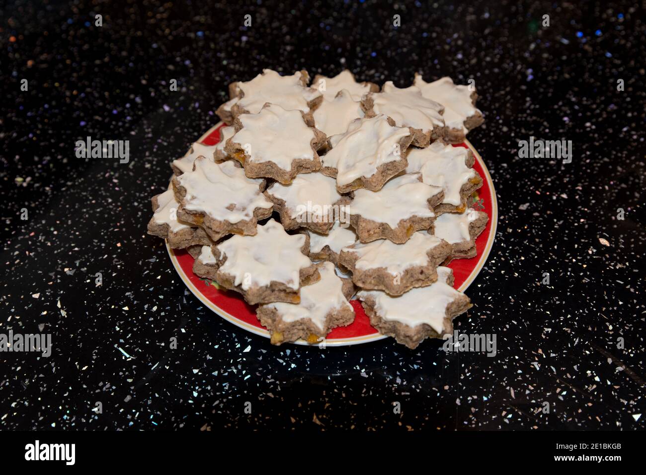 primo piano di deliziosi biscotti salati con ghiaccio bianco appena sfornati. Uno spuntino su un piatto si trovava su una superficie nera scintillante della cucina Foto Stock