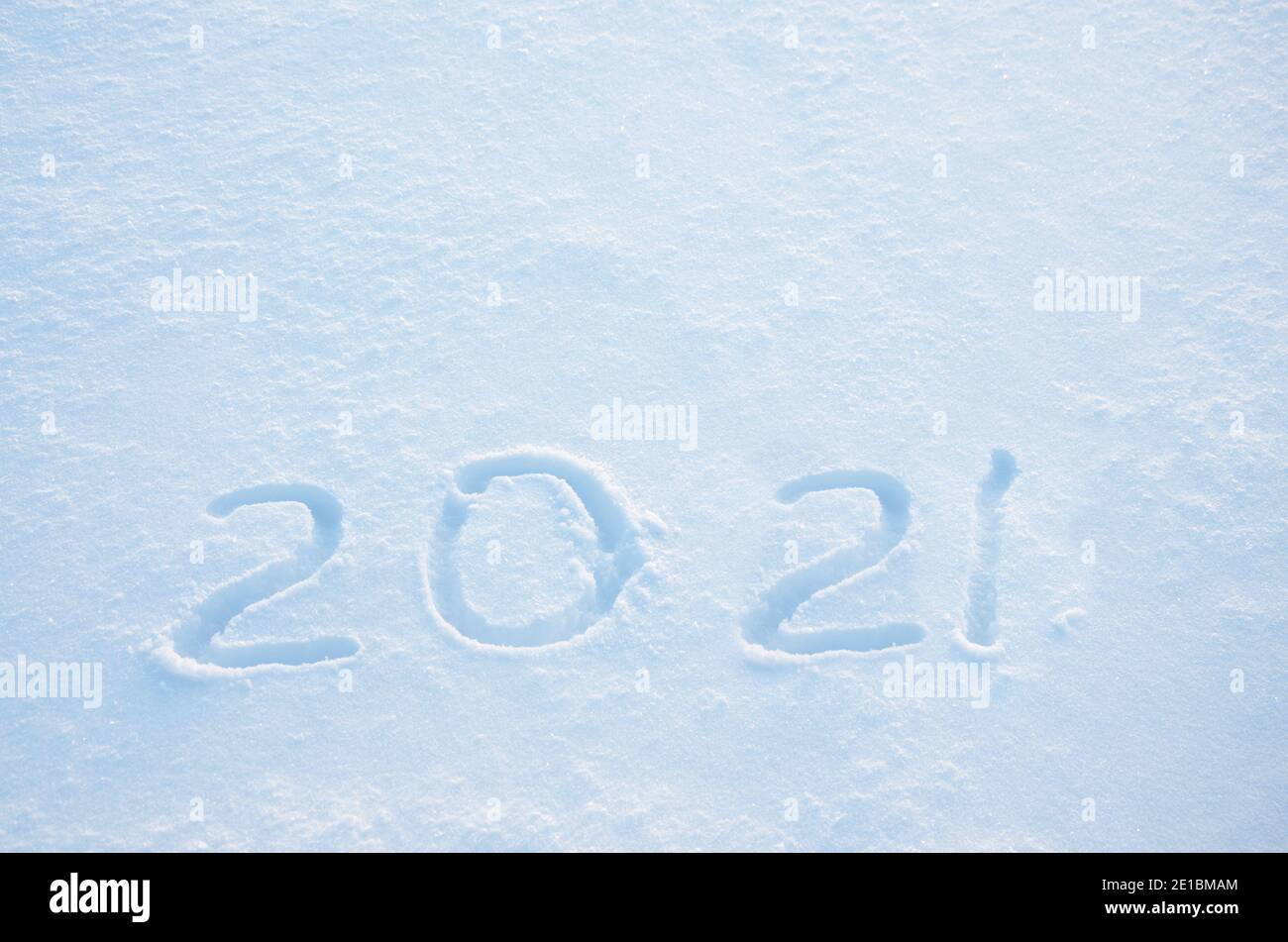 Cifre scritte a mano 2021 in una neve fresca e fresca illuminata dalla luce del sole nascente.concetto di anno nuovo. Foto Stock