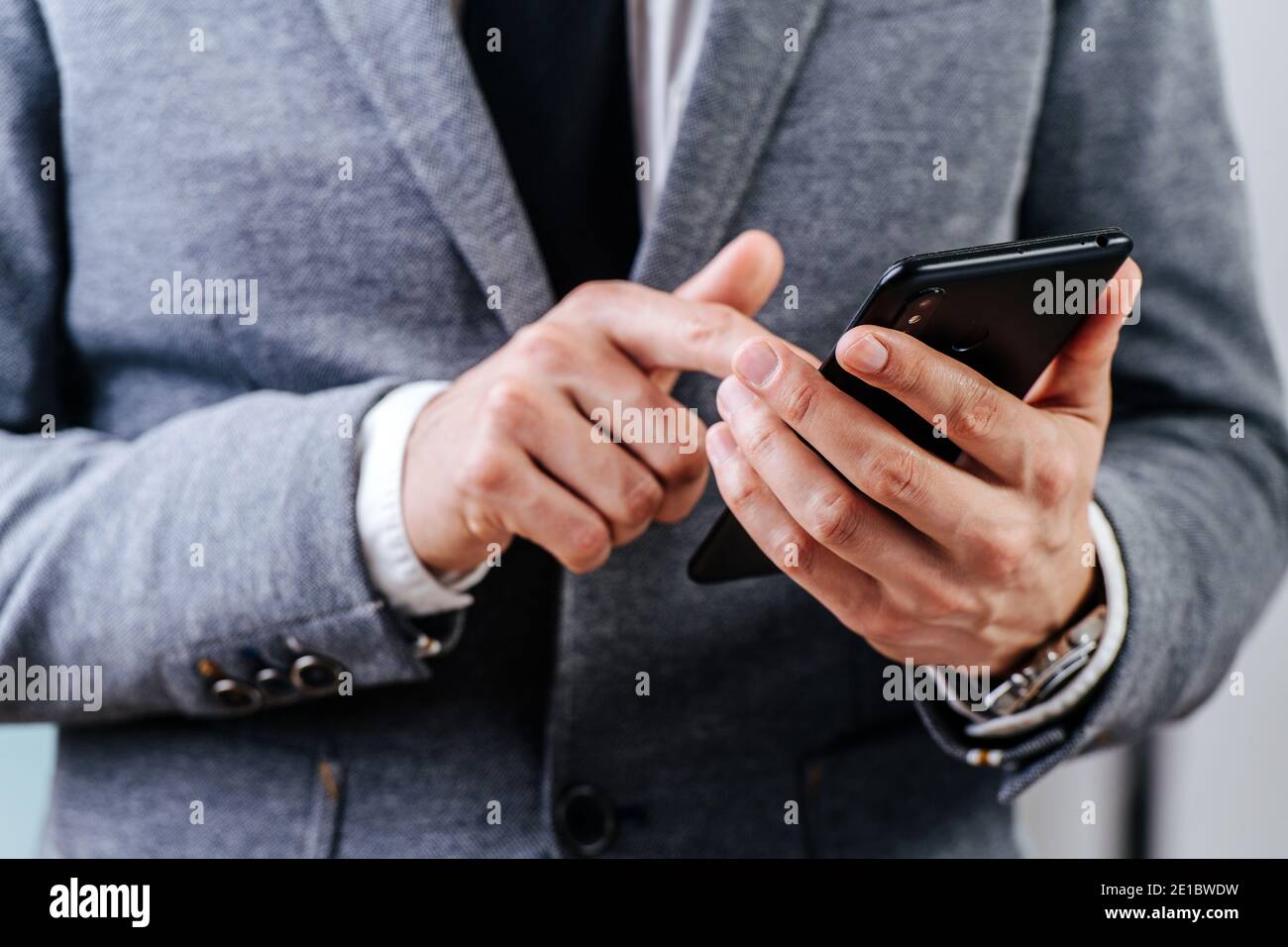 Immagine closeup delle mani di uomo d'affari, tiene il telefono e preme lo schermo Foto Stock