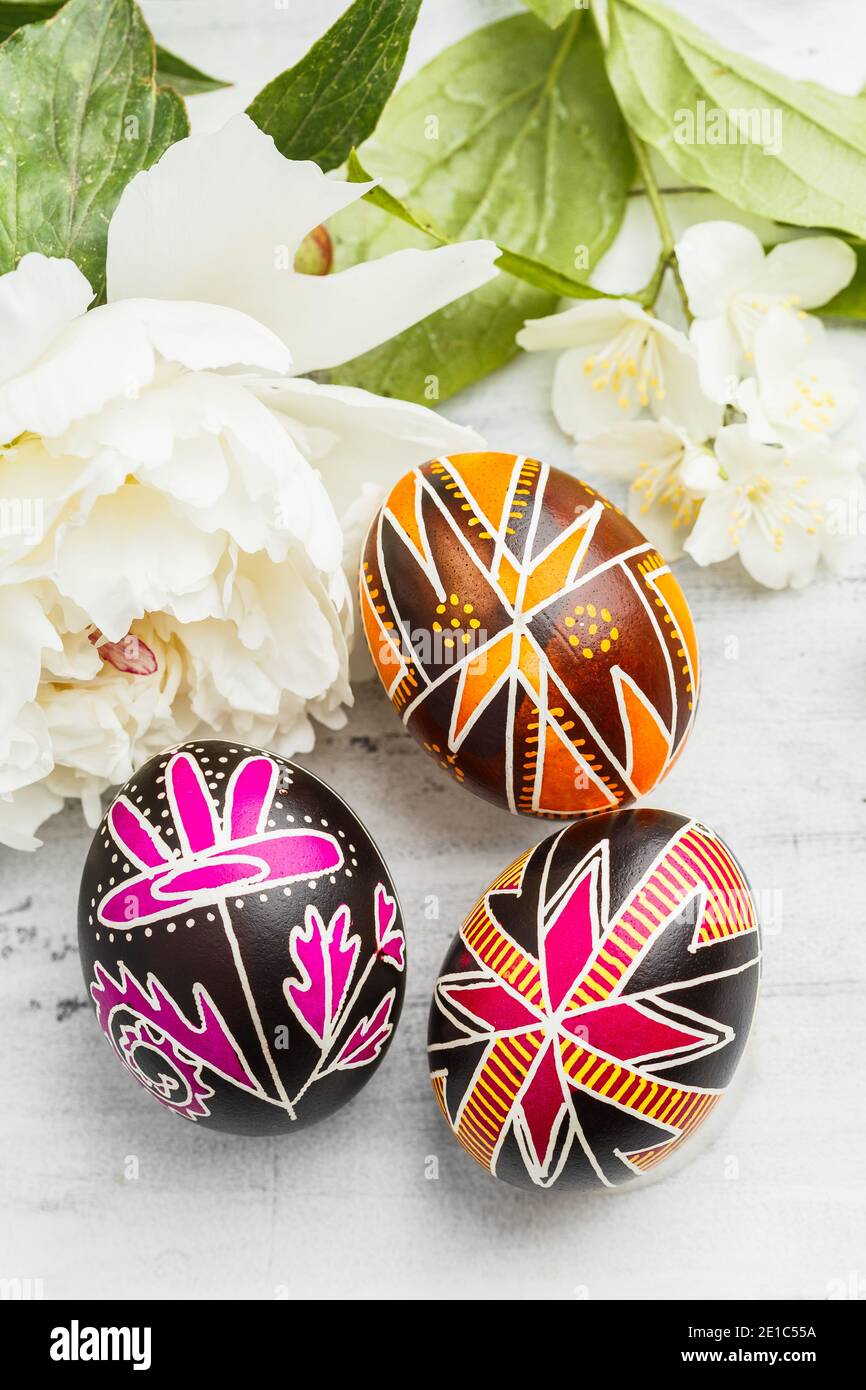 Tre uova di Pasqua fatte a mano decorate con tecnica di tintura resistente alla cera. Ucraino pysanky sul tavolo. Composizione verticale Foto Stock