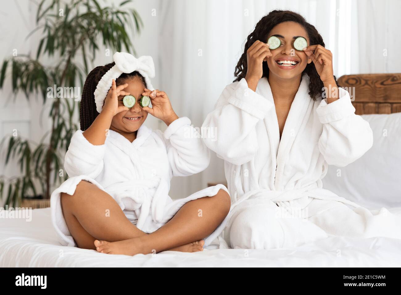 Gioiosa mamma nera e figlia in accappatoi avendo Beauty Day A casa Foto Stock