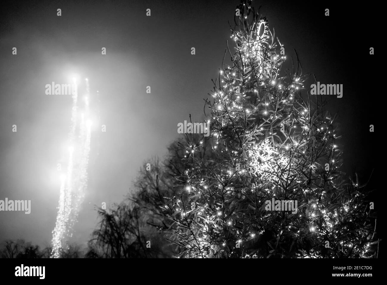 Albero di Natale decorato e fuochi d'artificio nel cielo. Bianco e nero. Foto Stock