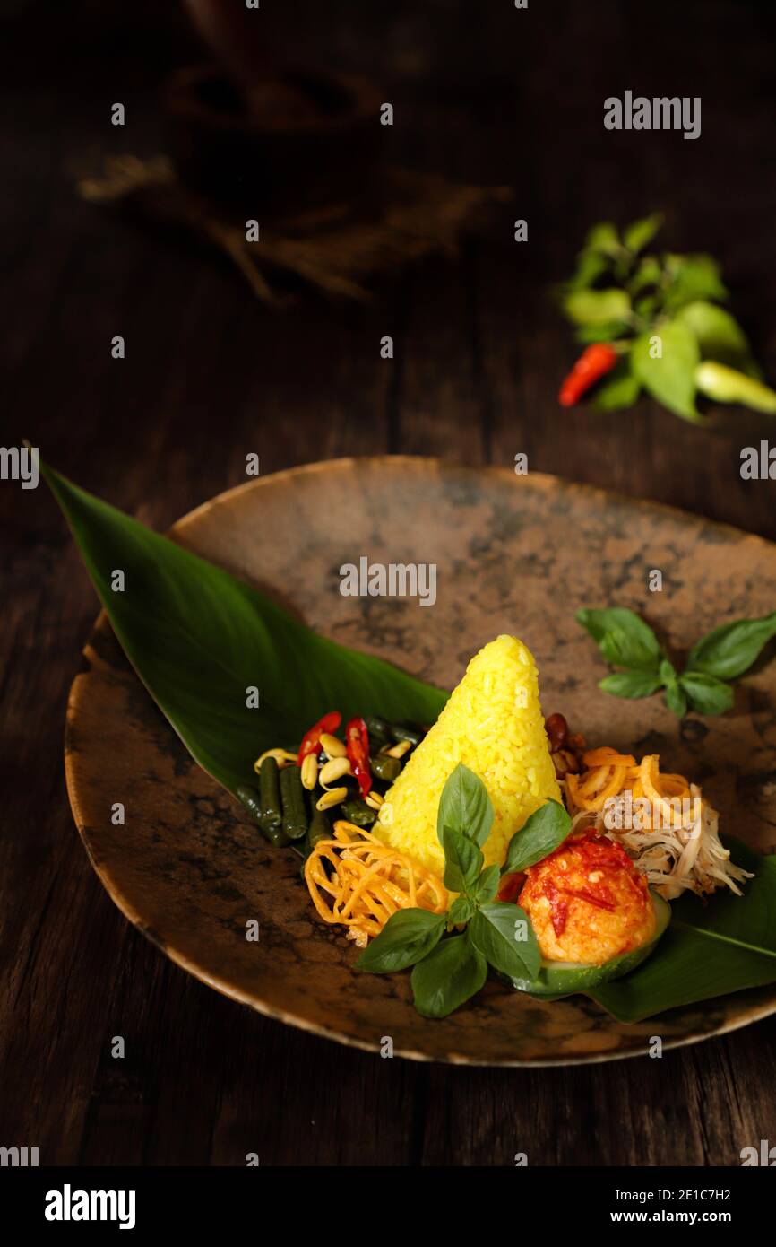 Nasi Kuning. Pasto festivo indonesiano di riso curcico con contorni. Foto Stock