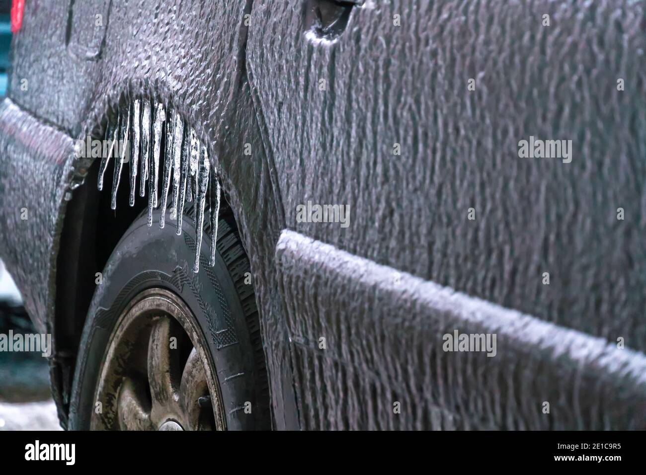 Primo piano di una carrozzeria ghiacciata con ghiaccio sopra la ruota posteriore primo piano. Foto Stock