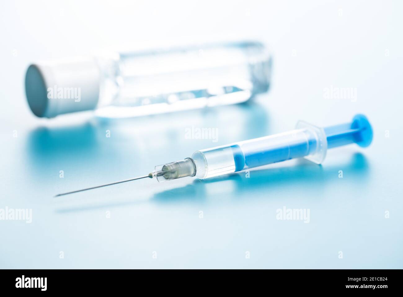 Siringa per iniezione e gel igienizzante. Vaccinazione con il coronavirus di Covid-19. Vaccino del virus corona su sfondo blu. Foto Stock