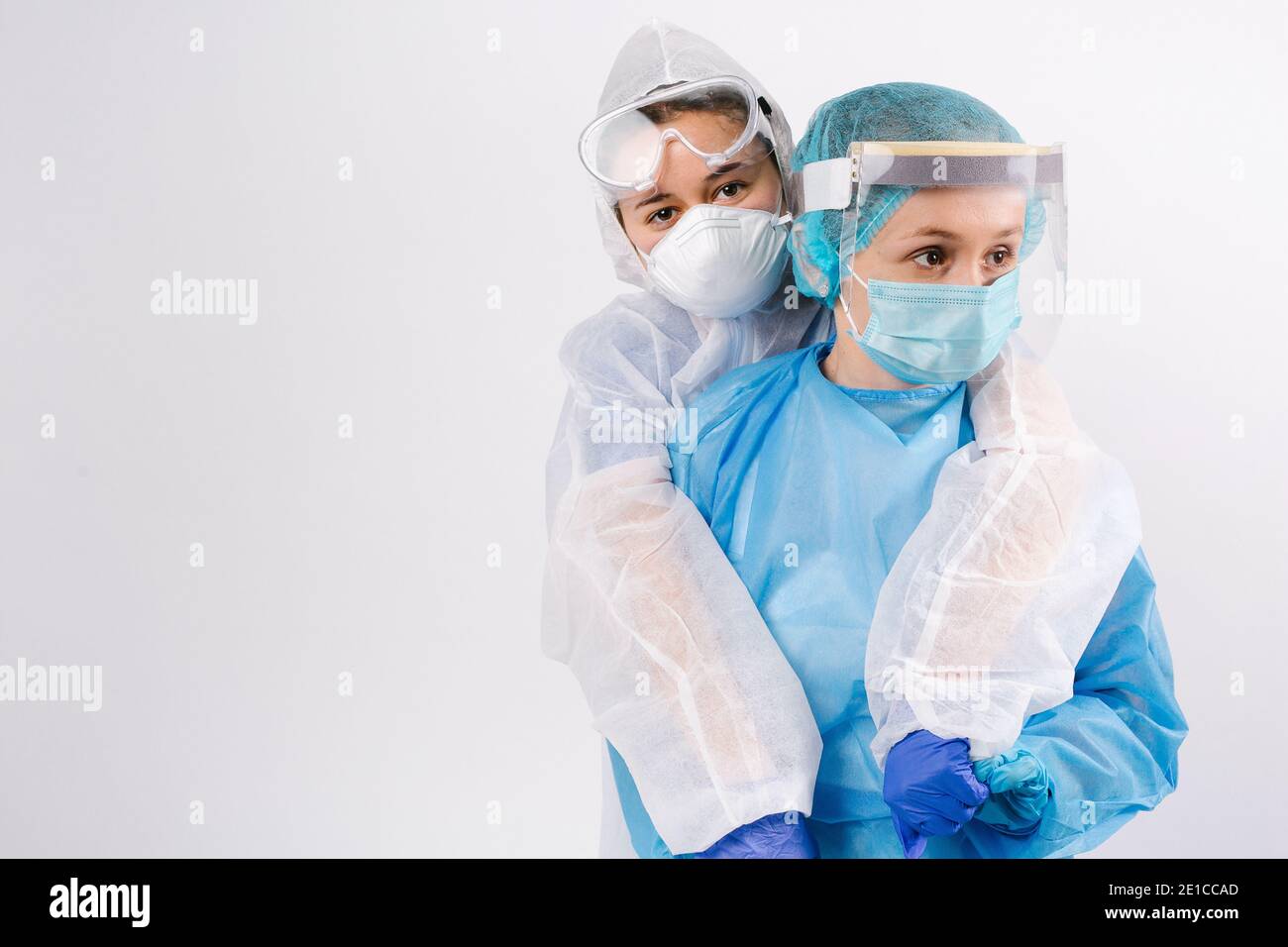 I medici stanchi in tute protettive sono abbracciati e sostenuti guardando al lato. Supporto in tempi difficili. Spazio laterale. Foto Stock