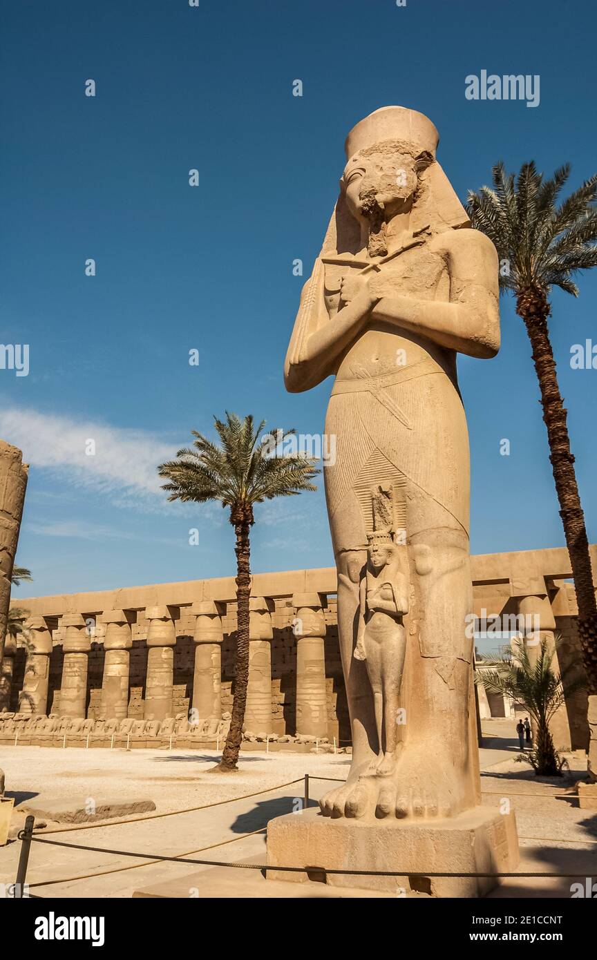 Luxor. Questa è la statua di Ramasses II, il Grande con sua figlia Bentanta ai piedi all'ingresso del tempio di Karnak, 4000 anni fa, il più grande complesso di templi del mondo, Situato sul fiume Nilo nella città di Luxor precedentemente conosciuta nel mondo antico come Tebe. I terreni del tempio furono utilizzati anche come set cinematografico per il film di James Bond The Spy Who Loved Me. Foto Stock