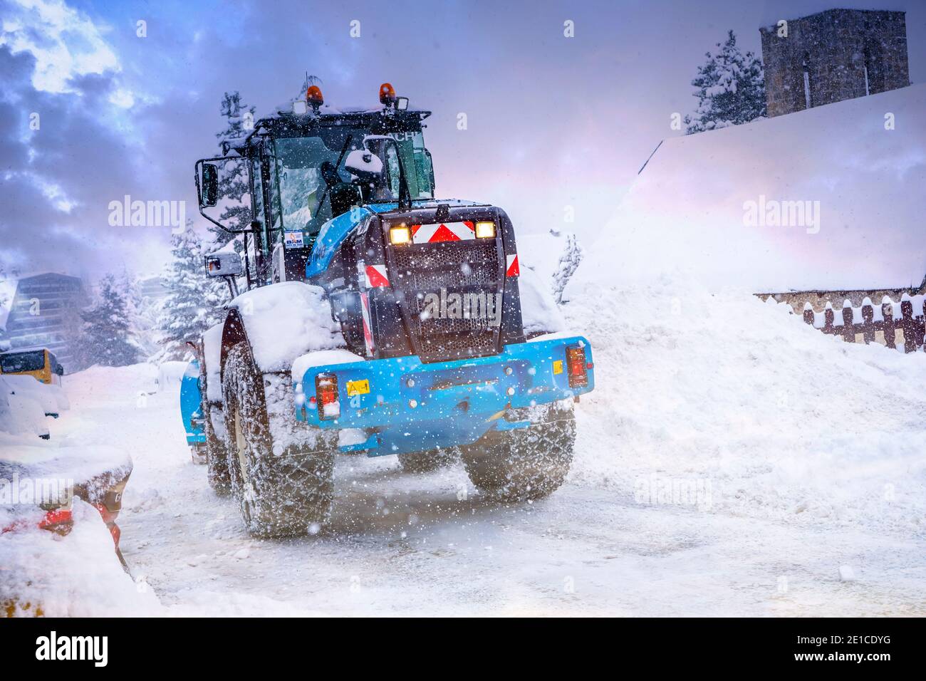 Auron, Francia 01.01.2021 trattore che rimuove la neve dalle grandi rive della neve vicino alla strada su una stazione sciistica. Foto di alta qualità Foto Stock