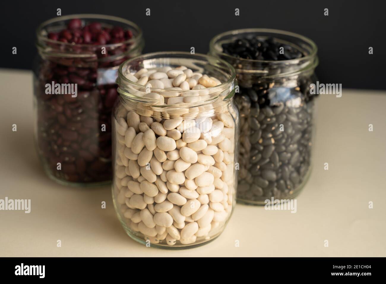 vaso di vetro con fagiolo nero, fagiolo rosso e fagiolo bianco. fagiolo blu, fagiolo bianco su sfondo bianco nero Foto Stock