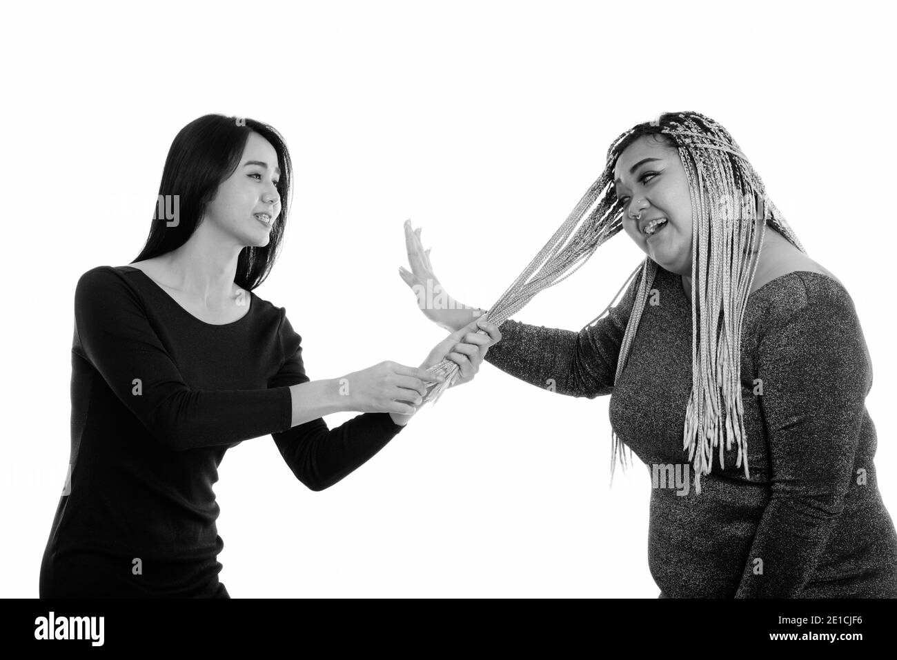 Giovani felici Asian transgender donna sorridente mentre si tira i capelli di grasso donna asiatica Foto Stock
