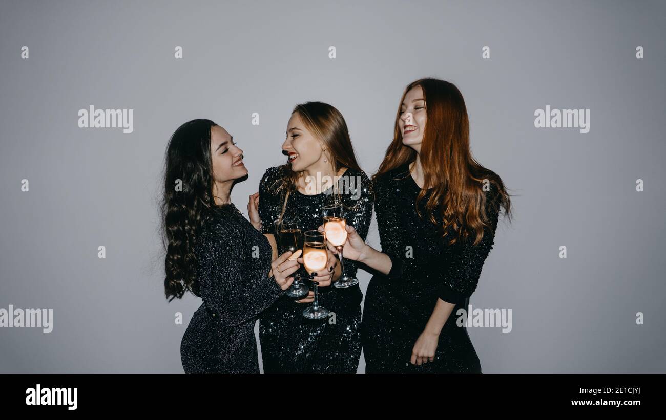 Anti-raduno nel tempo pandemico del coronavirus. Ospitare una festa di persona durante Covid, festa di casa con tre allegre amiche n brillantezza Foto Stock