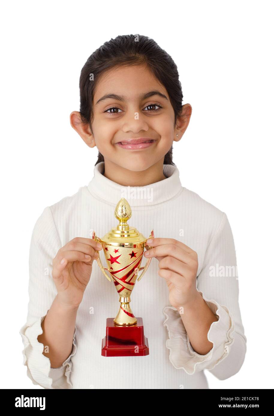 Ritratto di una bella e sorridente scuola indiana ragazza dentro sfondo bianco con un trofeo dorato e raffigurante il concetto vincente Foto Stock