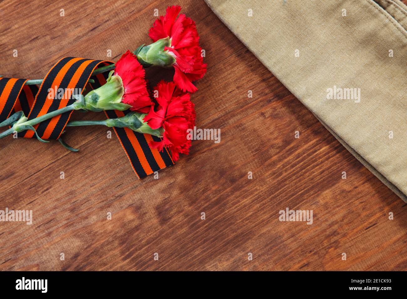 Tre fiore rosso e della carta e del soldato cappuccio di foraggio su uno sfondo di legno. messa a fuoco selettiva immagine Foto Stock