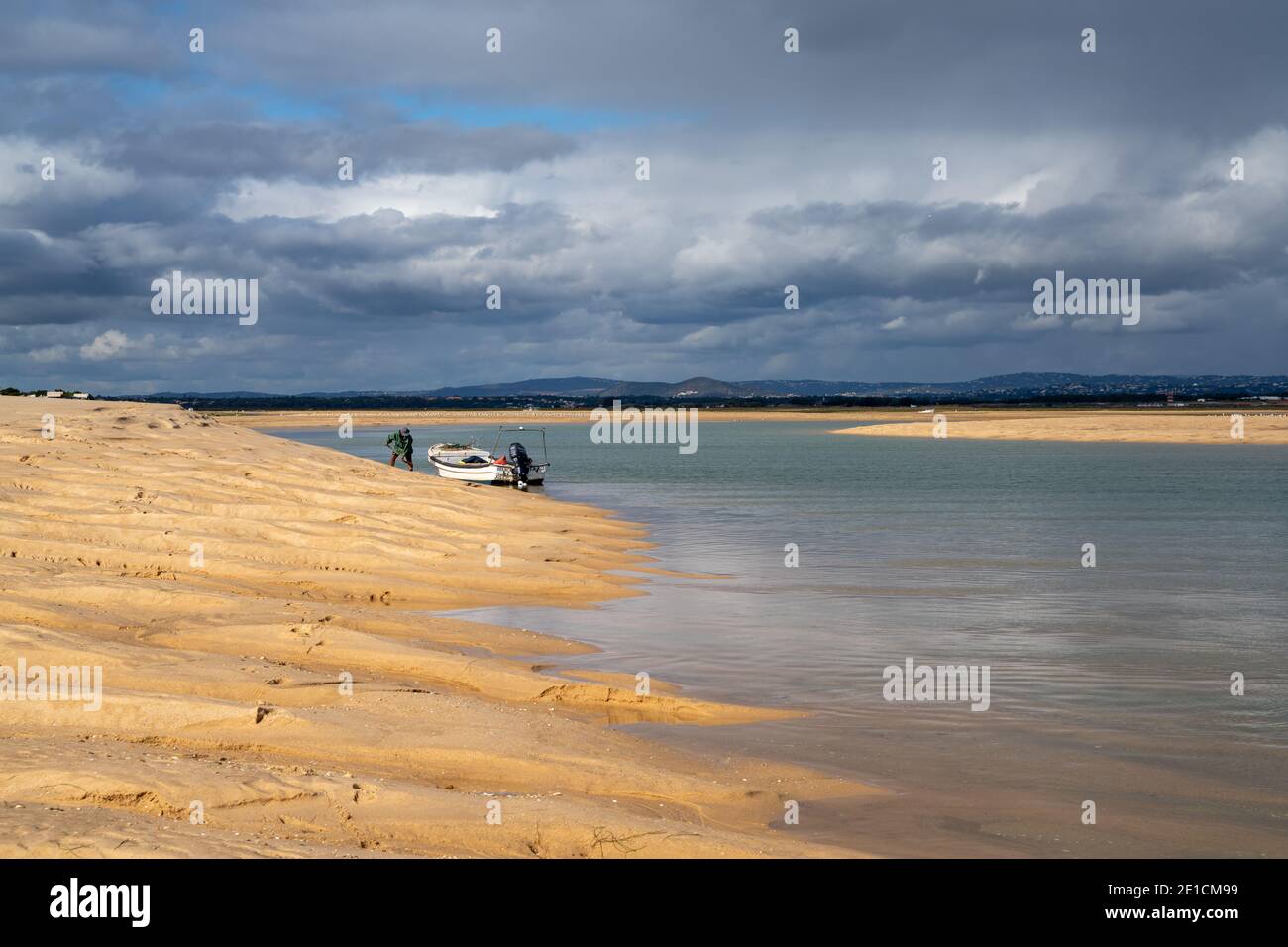 Faro, Portogallo - 4 gennaio 2021: Uomo che raccoglie sabbia per la farina di granchio e pesca nel delta del fiume Ria Formosa Foto Stock