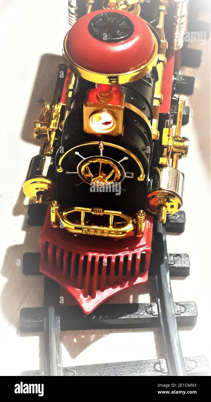 Ferrovia per bambini - la locomotiva si trova su rotaie nere sullo sfondo di laminato bianco. Vista dall'alto. Giocattoli per bambini. Trasporto Foto Stock