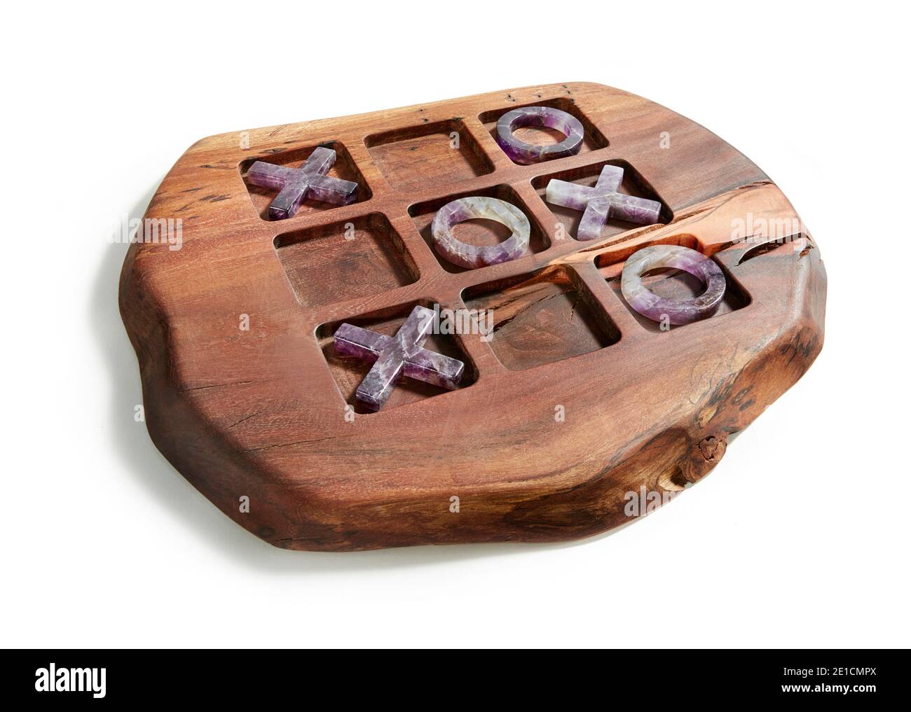 Tasselli tac tic in pietra viola su tavola da gioco in legno Disegnato da Anna Rabinowicz fotografato su sfondo bianco Foto Stock