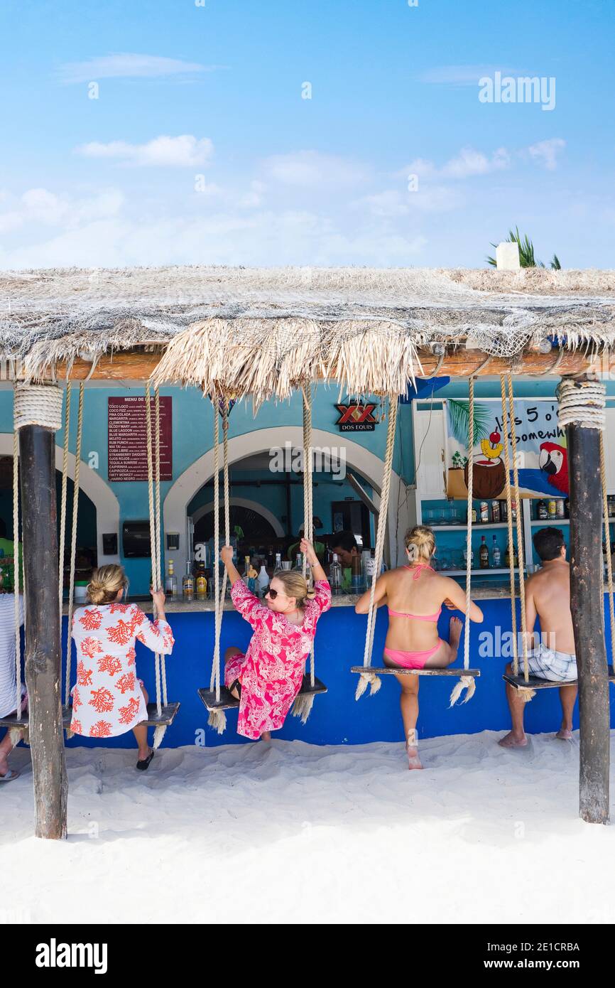Persone in altalene in un bar sulla spiaggia Foto Stock