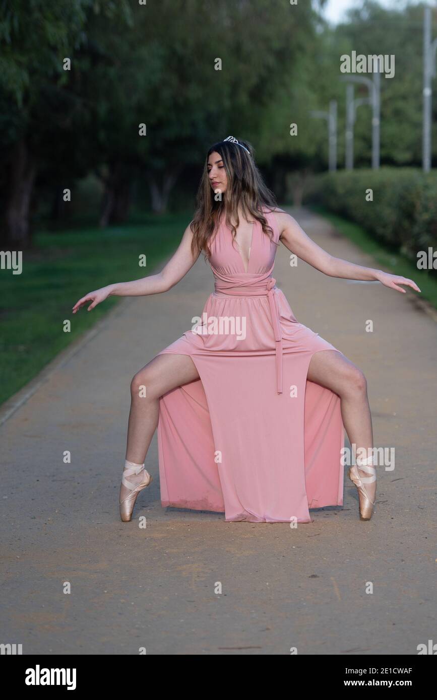 Giovane donna adolescente che indossa un abito rosa in piedi sulla danza pointe balletto all'aperto Foto Stock