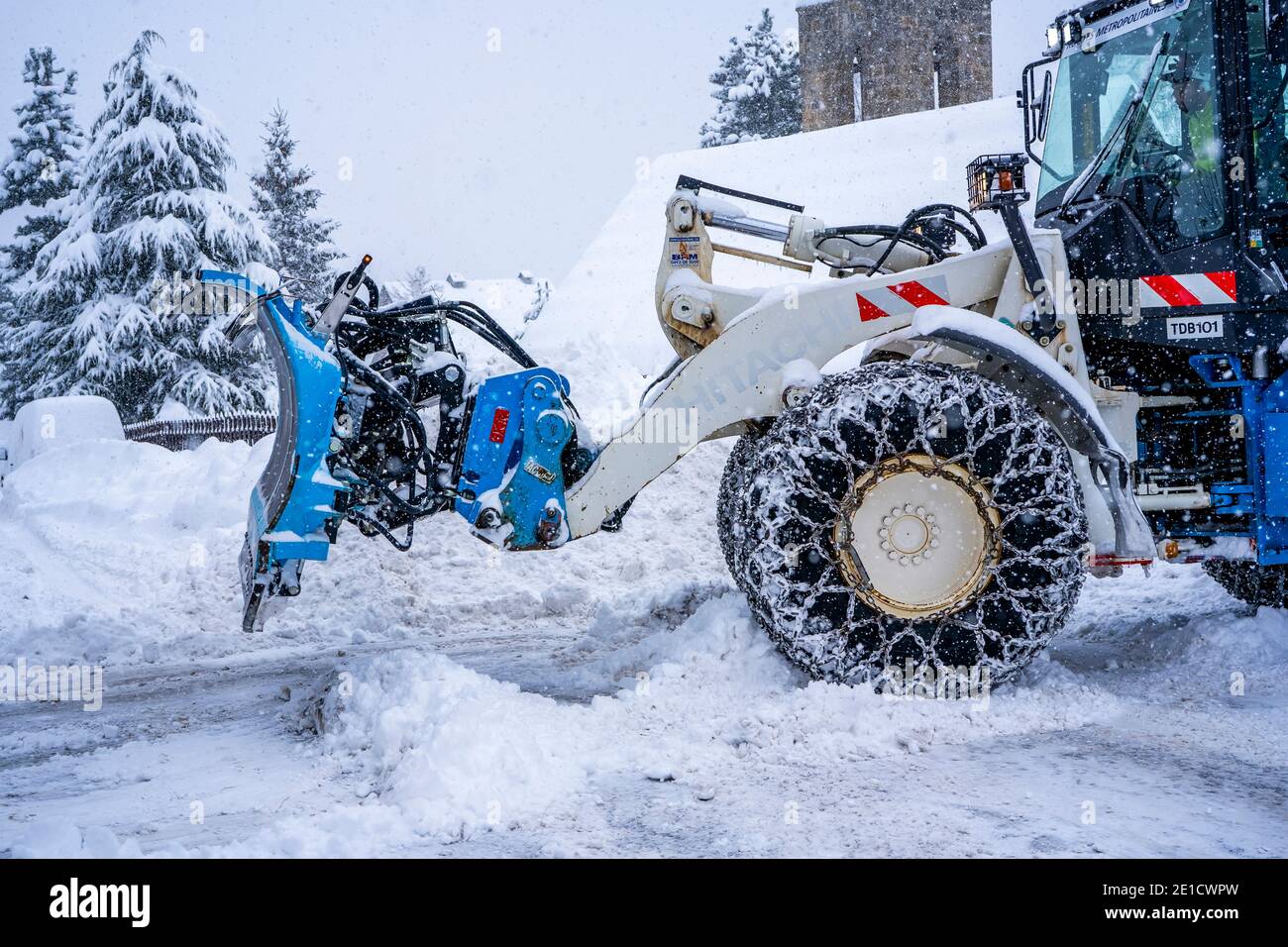 Auron, Francia 01.01.2021 trattore che rimuove la neve dalle grandi rive della neve vicino alla strada su una stazione sciistica nelle Alpi francesi. Foto di alta qualità Foto Stock