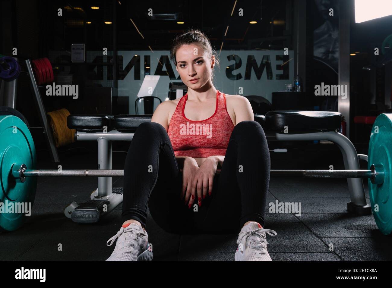 Giovane bella atletica donna pone con campane in palestra. La donna preparata a fare deadlift pone per la telecamera. Foto Stock