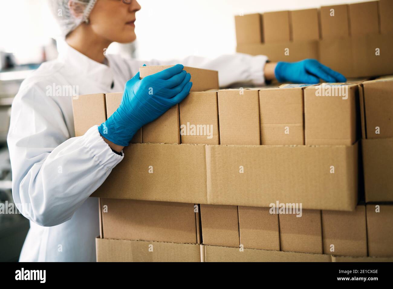 La lavoratrice specializzata in abiti sterili conta scatole pronte per la consegna. Foto Stock